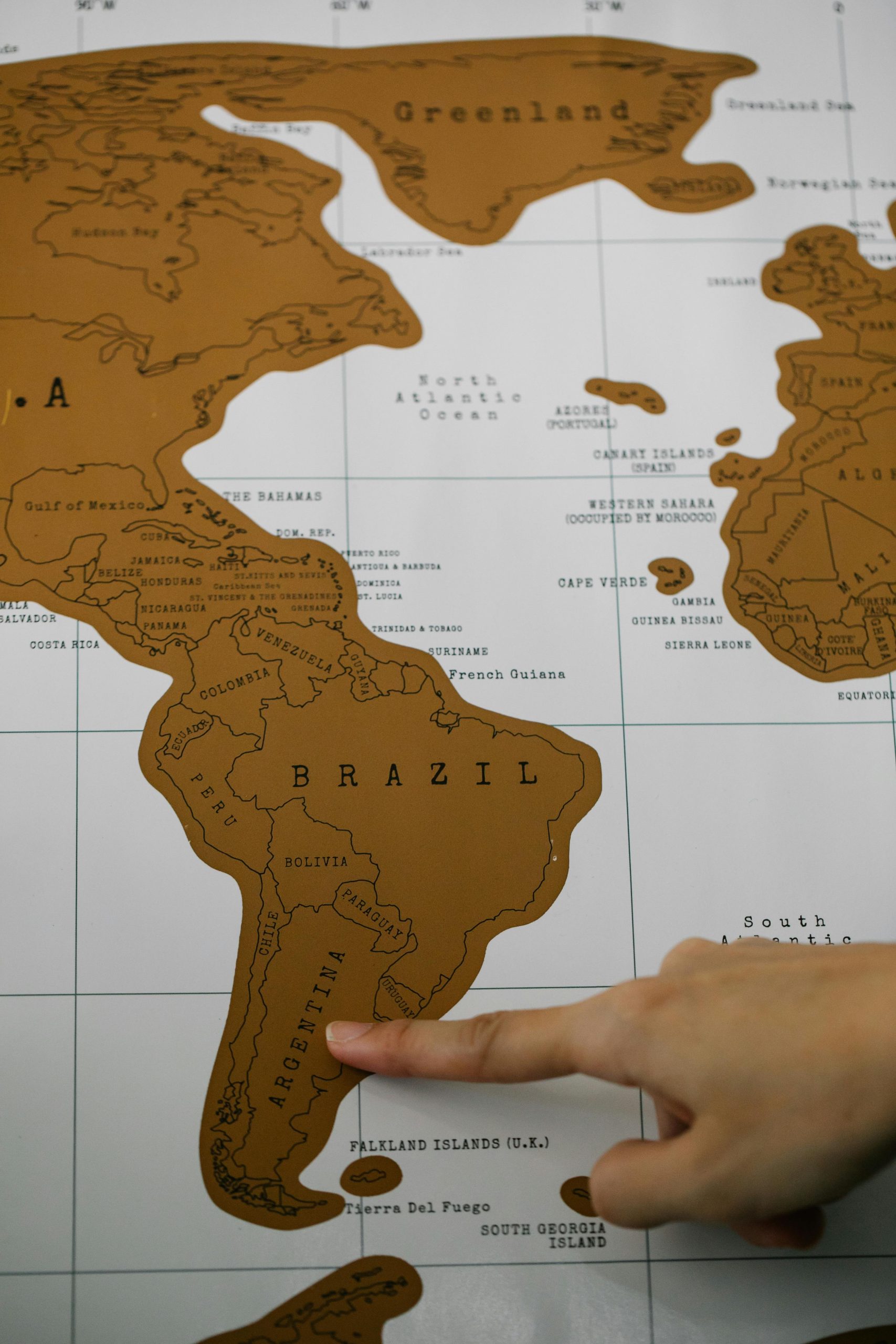 Close-up of a hand pointing to a map of South America for geographical reference.