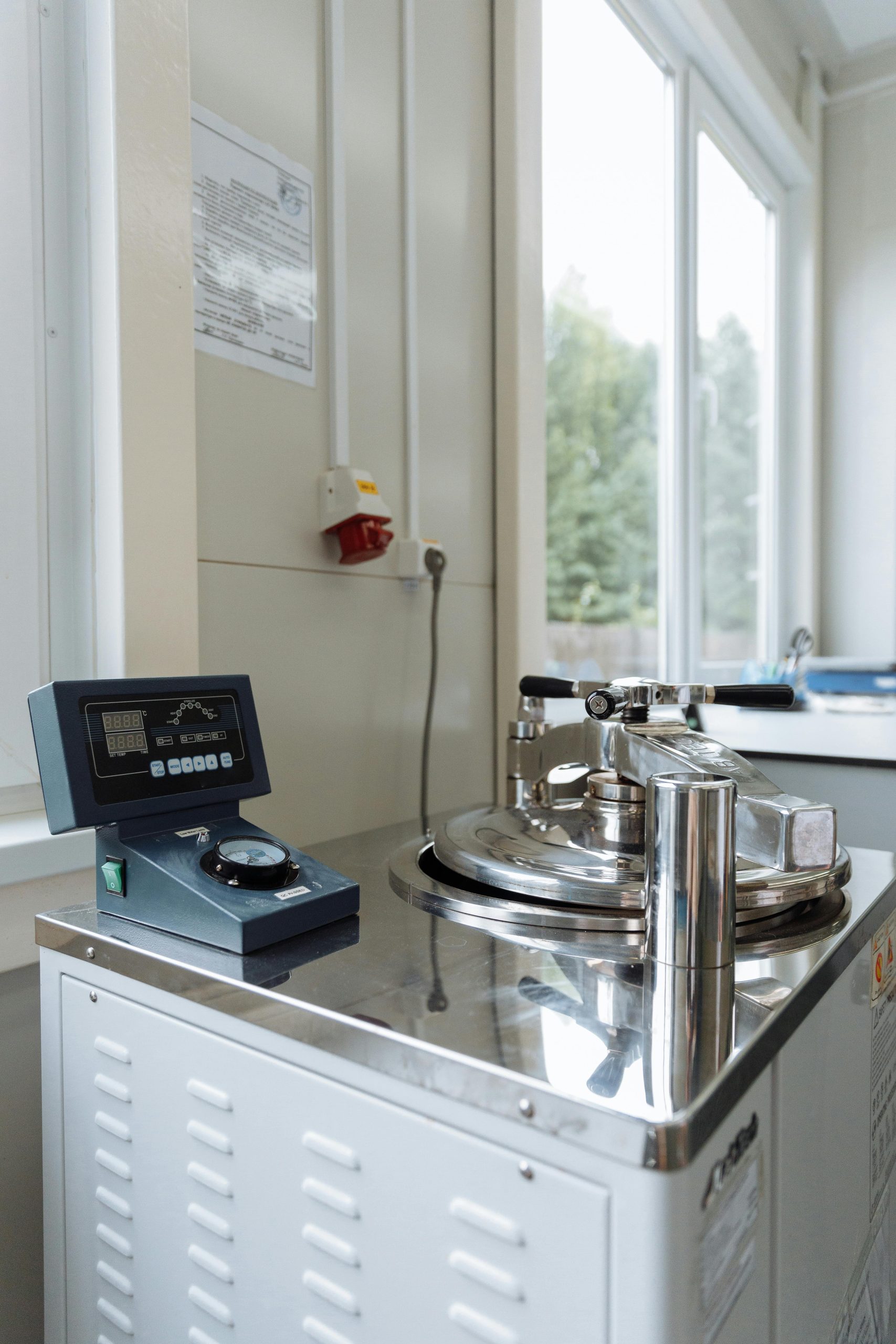 Modern laboratory equipment with stainless steel finish in a sterile setting near windows.